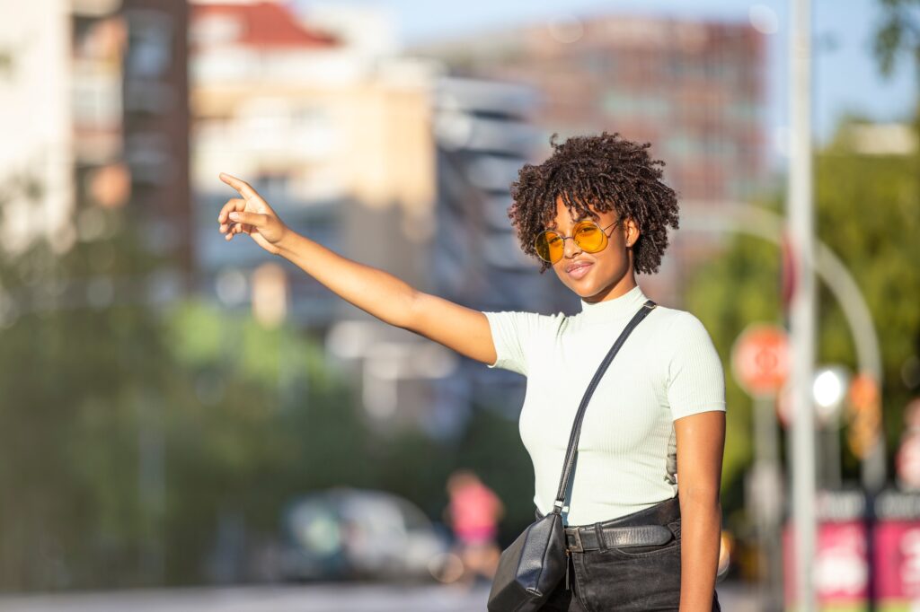 Latin American young woman trying to stop a taxi in the city